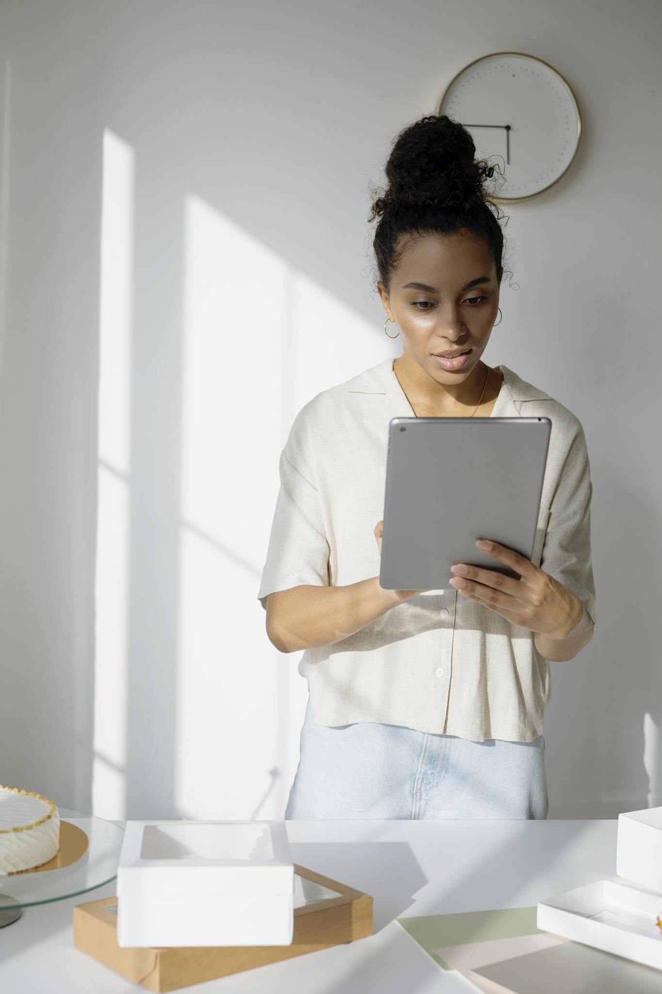Young woman using tablet in a bright home office setting, managing online business.